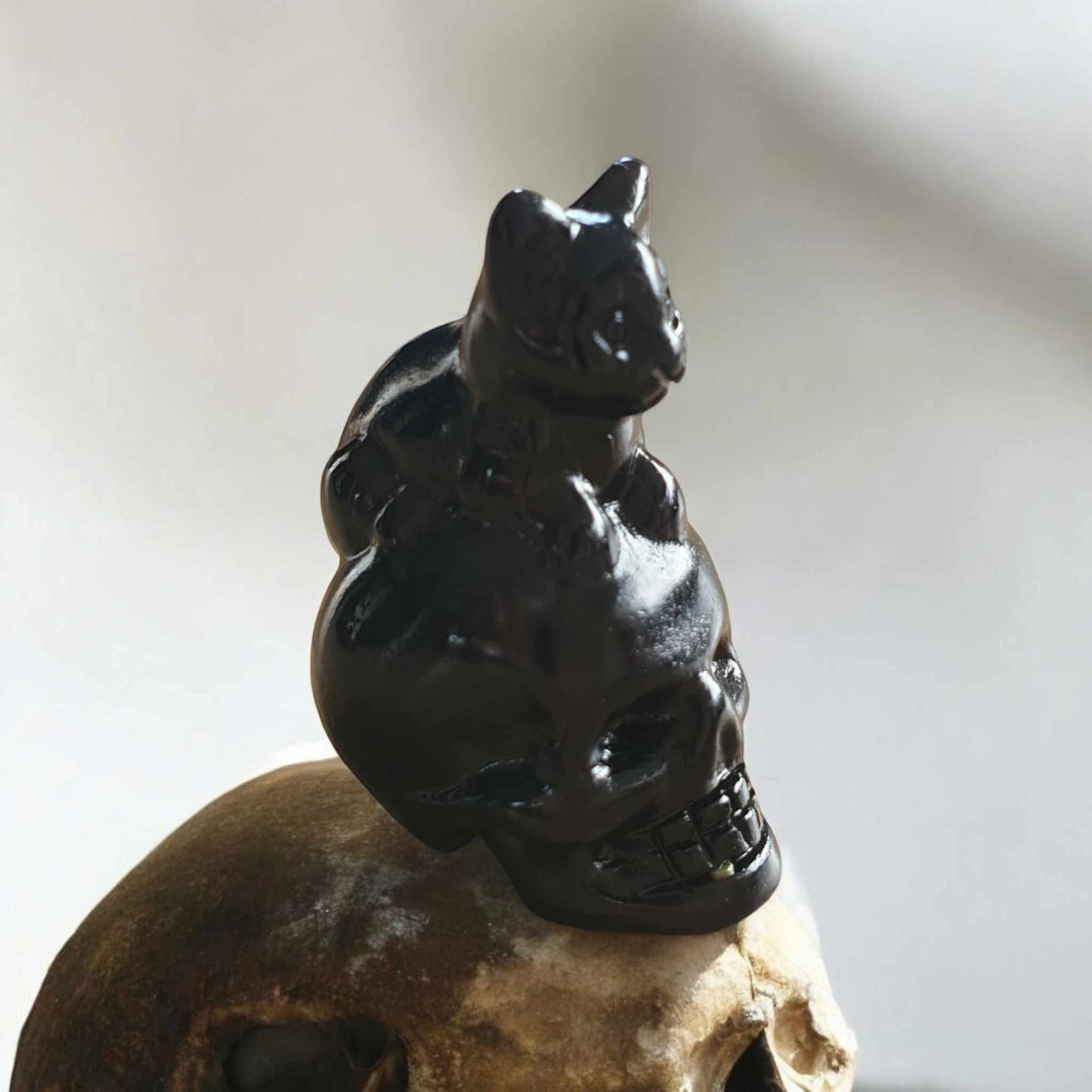 Petite Sculpture de Chat Assis sur une Tête de Mort en Obsidienne Noire – 3 cm de Hauteur